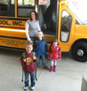 Woman and children standing in front of newly purchased school bus.