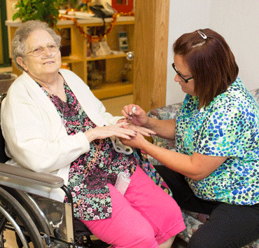 Caregiver painting nails of elderly patient.