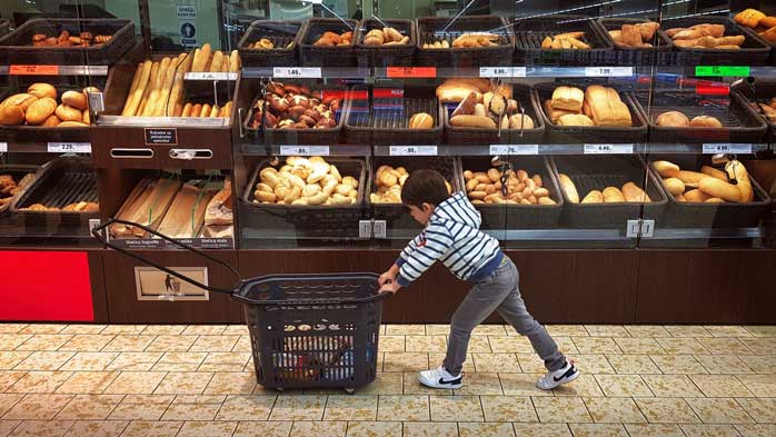 Child pushing cart through grocery store