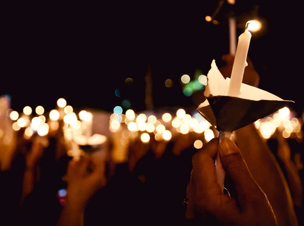 People holding candles in the air at nighttime vigil